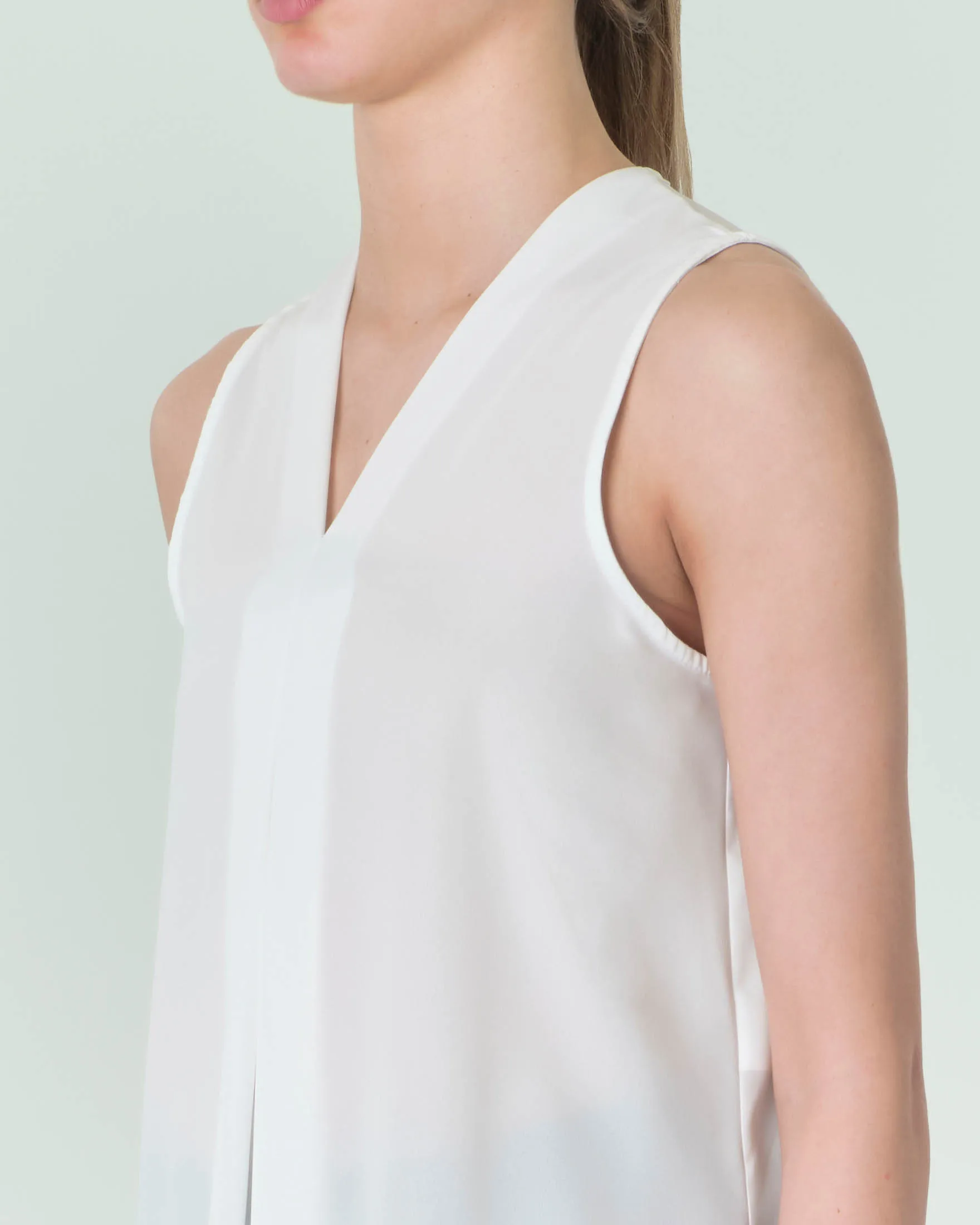 Top smanicato bianco in georgette dalla linea svasata con piega a cannone frontale